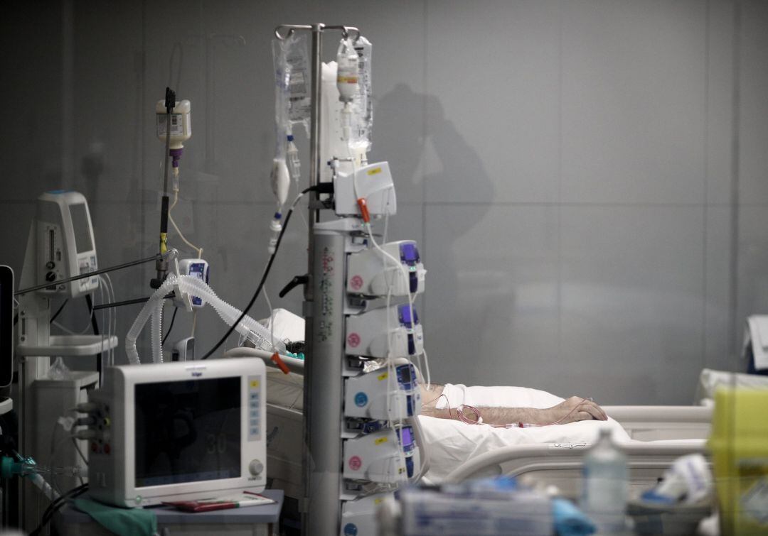 Mano de un enfermo con vía subcutánea en una cama de la UCI del Hospital de Emergencias Isabel Zendal (Madrid)