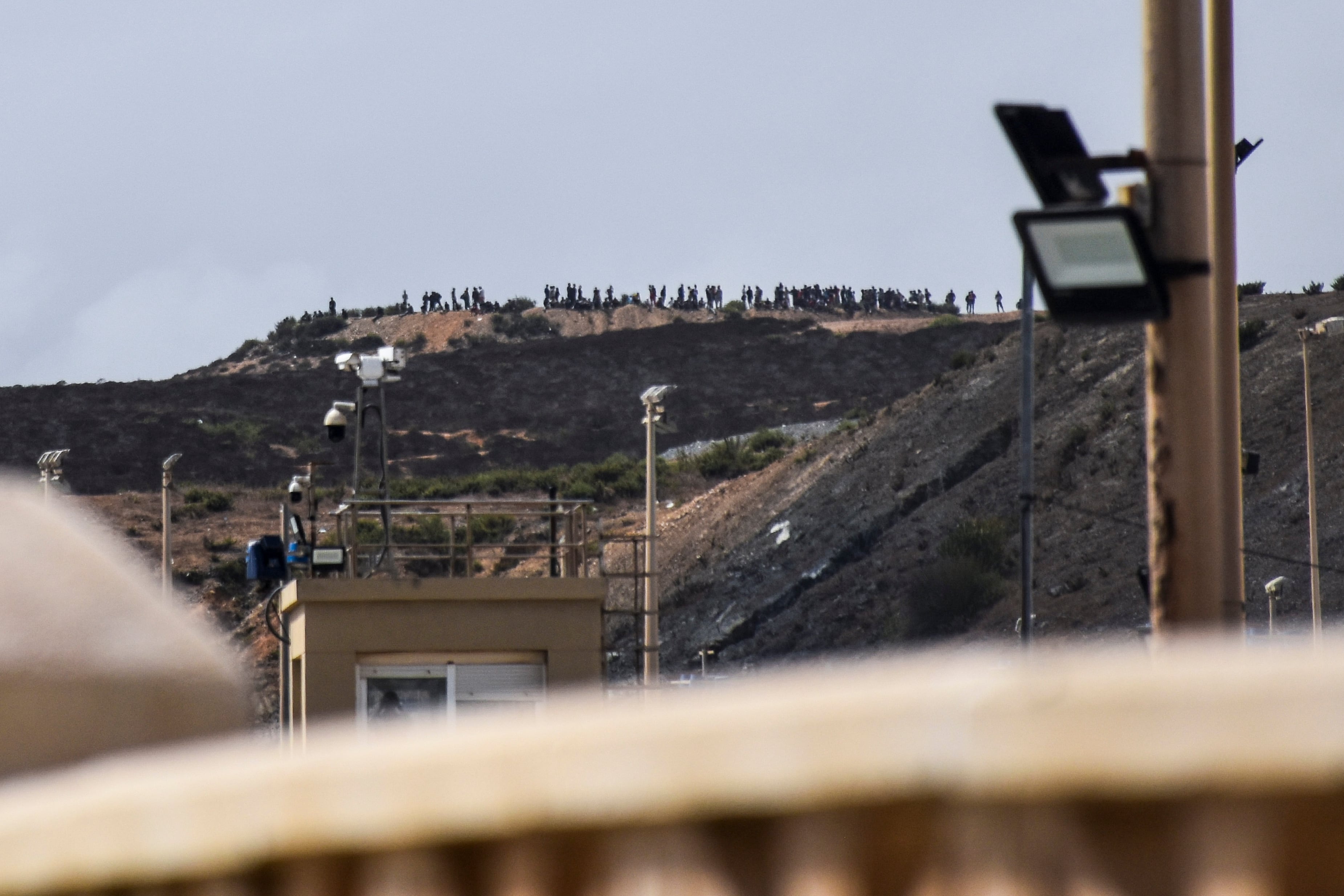 Decenas de personas se congregan en un monte cercano a la frontera con Ceuta para intentar cruzar a la ciudad española. La policía está cerrando de forma intermitente la frontera del Tarajal, que separa Ceuta de Marruecos.