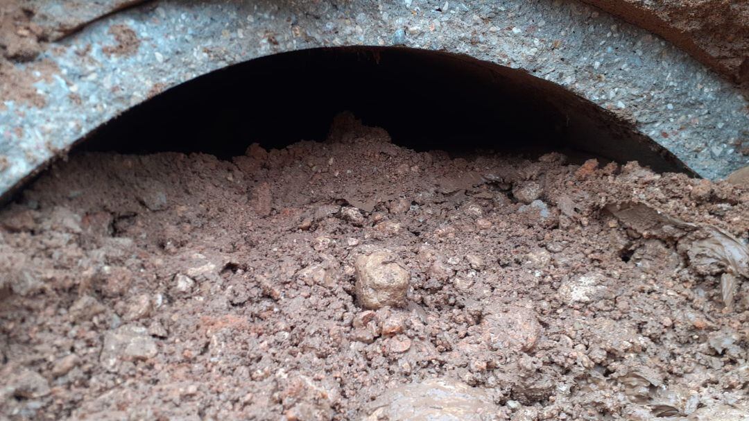Uno de los tubos anegados por barro y piedras