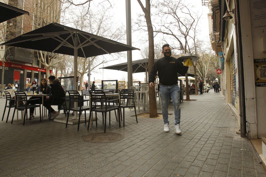 Un camarero atiende a varios clientes en la terraza de un bar 