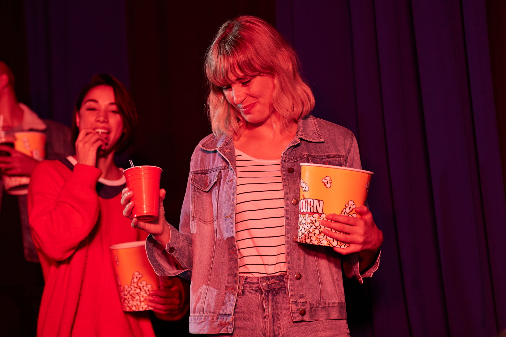 Una mujer con palomitas y refresco en el cine.