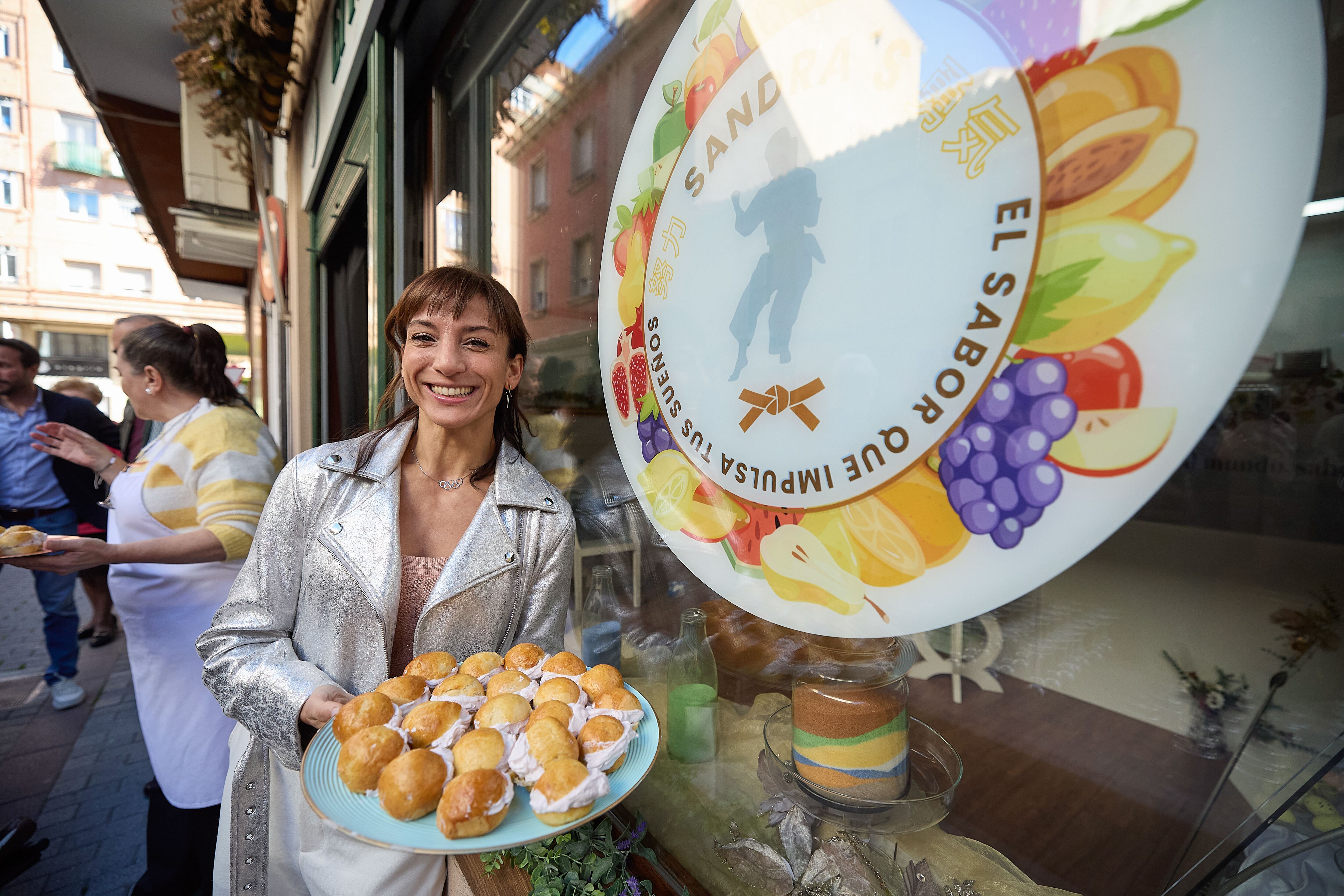 TALAVERA DE LA REINA (CASTILLA LA MANCHA), 31/03/2025.- La campeona olímpica Sandra Sánchez posa junto al homenaje en forma de dulce de la pastelería `El Horno de Santa Casilda´ de Talavera de la Reina (Castilla la Mancha) este lunes. `El Horno de Santa Casilda´ ha creado siete bambas con sabores diferentes, uno por cada uno de los cinturones del kárate. En la presentación del dulce, que ha tenido lugar este lunes en la pastelería, la propietaria del establecimiento, Inmaculada González, ha explicado que ha querido rendir homenaje a Sandra por su carrera profesional y por ser una persona maravillosa. EFE/ Manu Reino