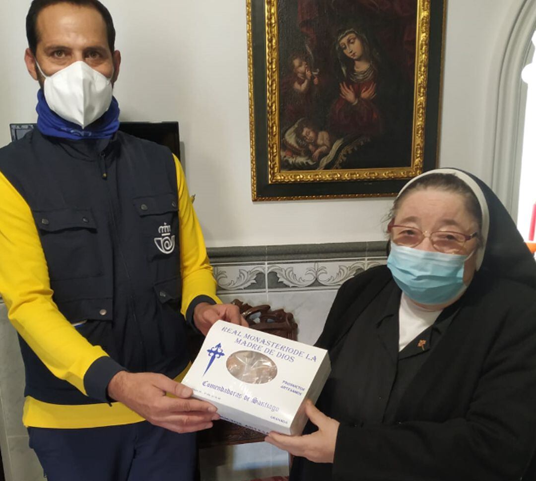 Un empleado de Correos recoge de una de las madres del monasterio de las Comendadoras de Santiago de Granada una de las cajas con sus dulces de Navidad para enviarla por el servicio de paquetería de la empresa estatal