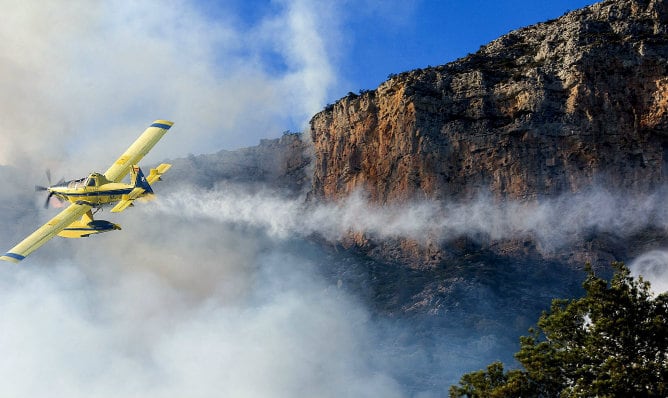 Una avioneta vierte agua durante las labores de extinción del incendio forestal declarado a los pies del Parque Natural del Montgó