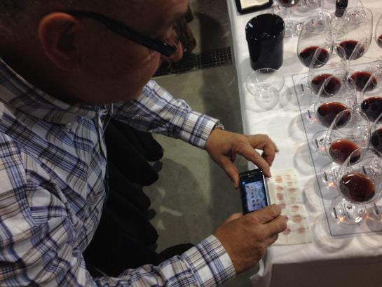 Uno de los participantes en la cata, fotografiando una rudimentaria escala cromática de los 14 vinos participantes.