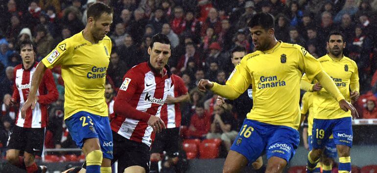 Los defensas de Las Palmas Dani Castellano (i) y Aythami Artiles (d) ante el delantero del Athletic de Bilbao Aritz Aduriz (c) durante el encuentro de la decimoctava jornada de Liga, disputado entre ambos equipos en el estadio de San Mamés de Bilbao