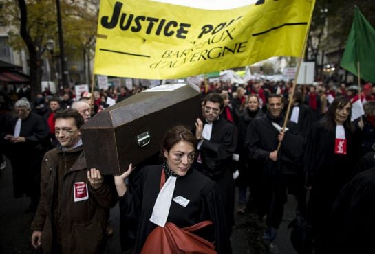 Unos abogados franceses participan en una manifestación simulando asistir a un entierro durante una protesta en contra de la &quot;ley Macron&quot; en París.