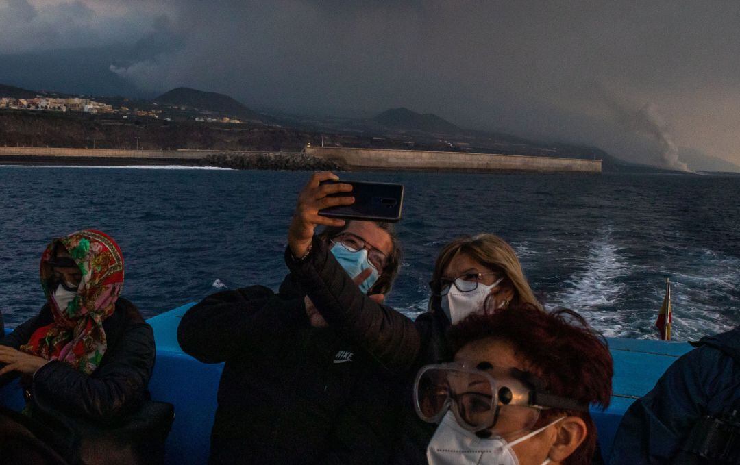 Un grupo de turistas fotografían la erupción volcánica en un barco que sale desde el puerto de Tazacorte.