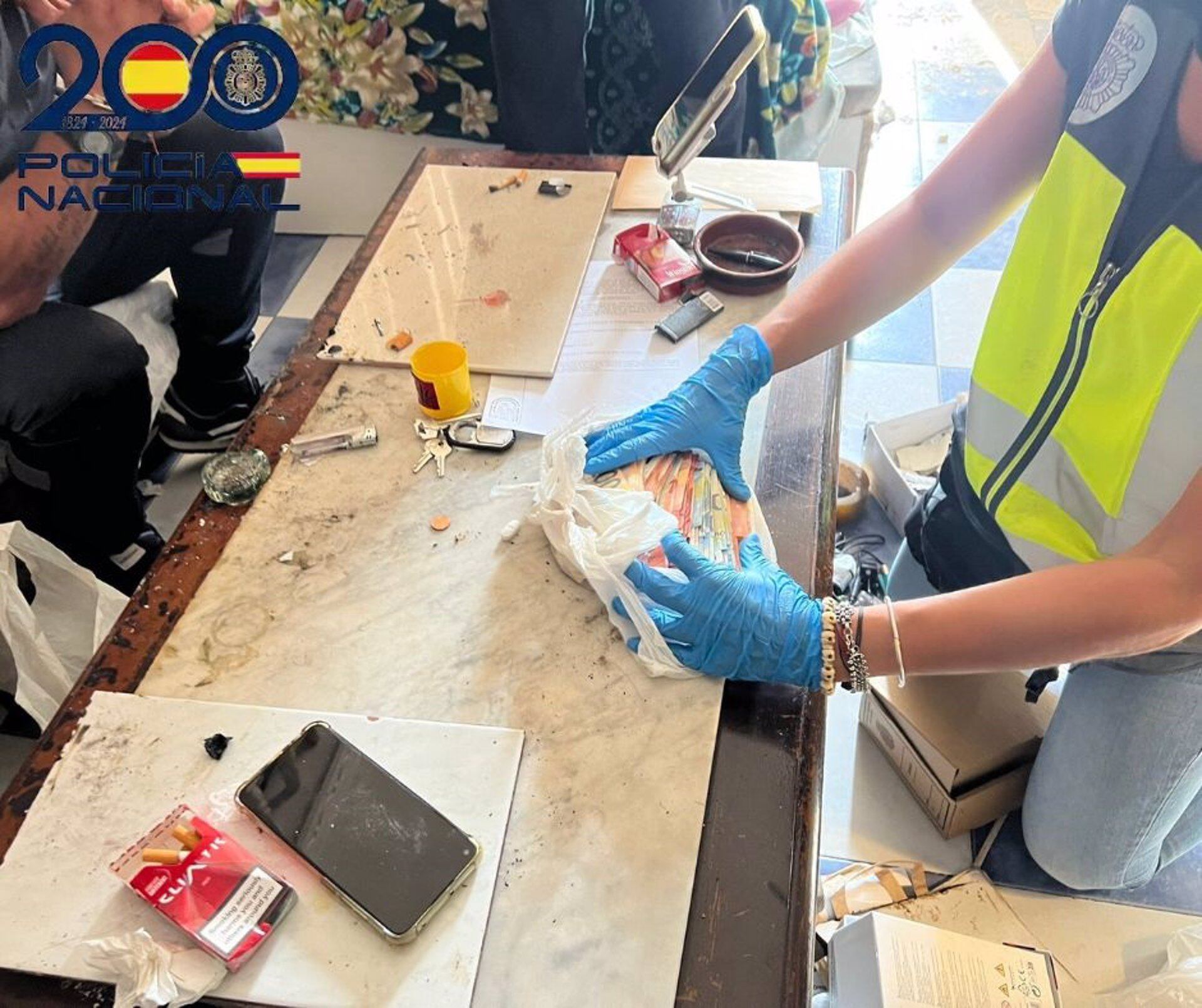 Un agente de la Policía contando dinero intervenido en el 'narcopiso' en Sanlúcar