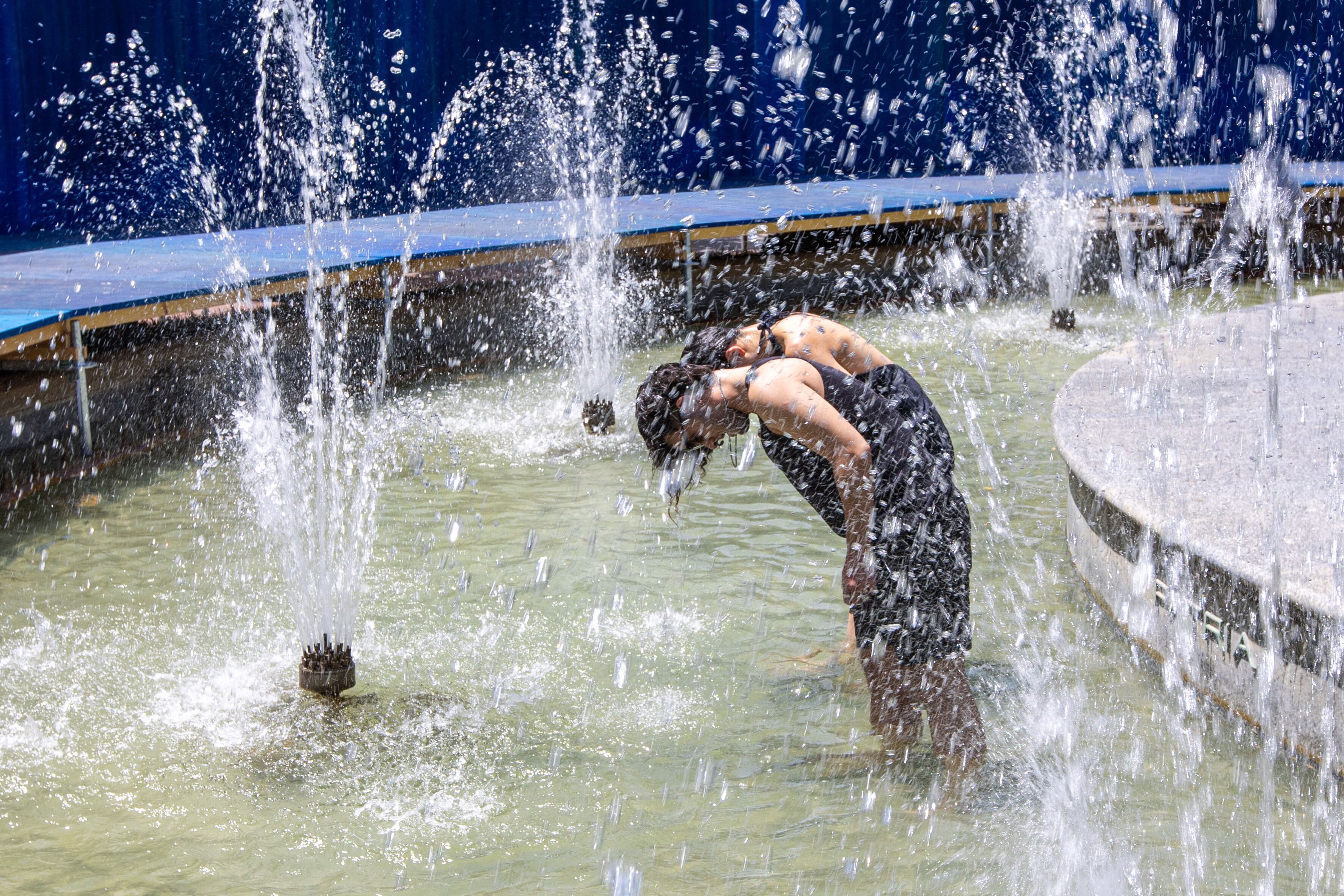 LOGROÑO 20/06/2025.- Unos jóvenes se refrescan en una de las obras de Concéntrico, ?Monumental Splash, ?que transforma por unos días la Fuente de Espartero en un oasis urbano compartido, invitando a los ciudadanos a refrescarse y a repensar el papel de los monumentos y del agua como elementos clave para enfrentar el calor extremo y el cambio climático. La Dirección General de Salud Pública, Consumo y Cuidados del Gobierno de La Rioja ha activado el nivel 2 (naranja) del 'Plan de alerta, prevención y control de los efectos del calor.-EFE/Raquel Manzanares
