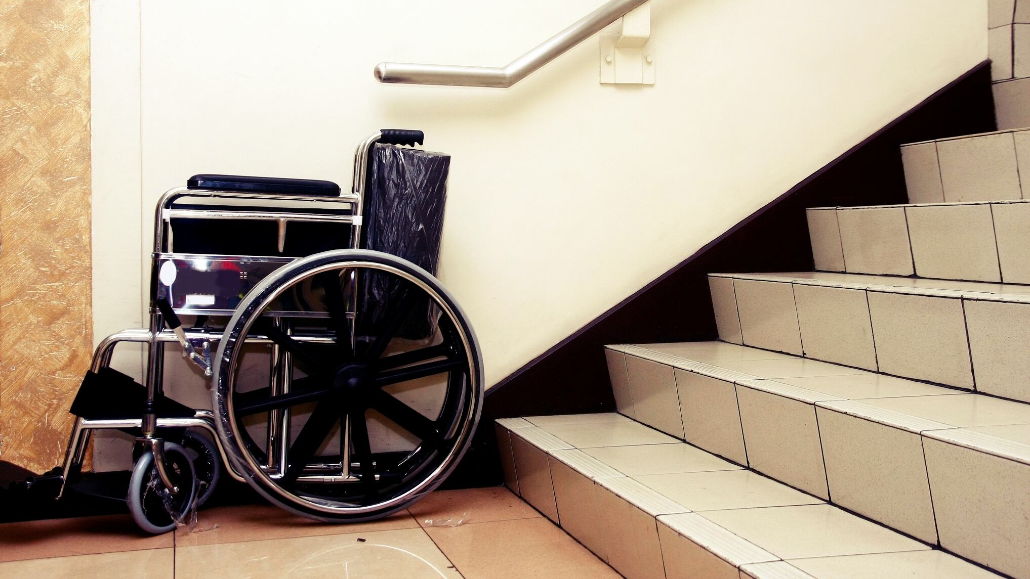 Silla de ruedas junto a las escaleras de un edificio de viviendas