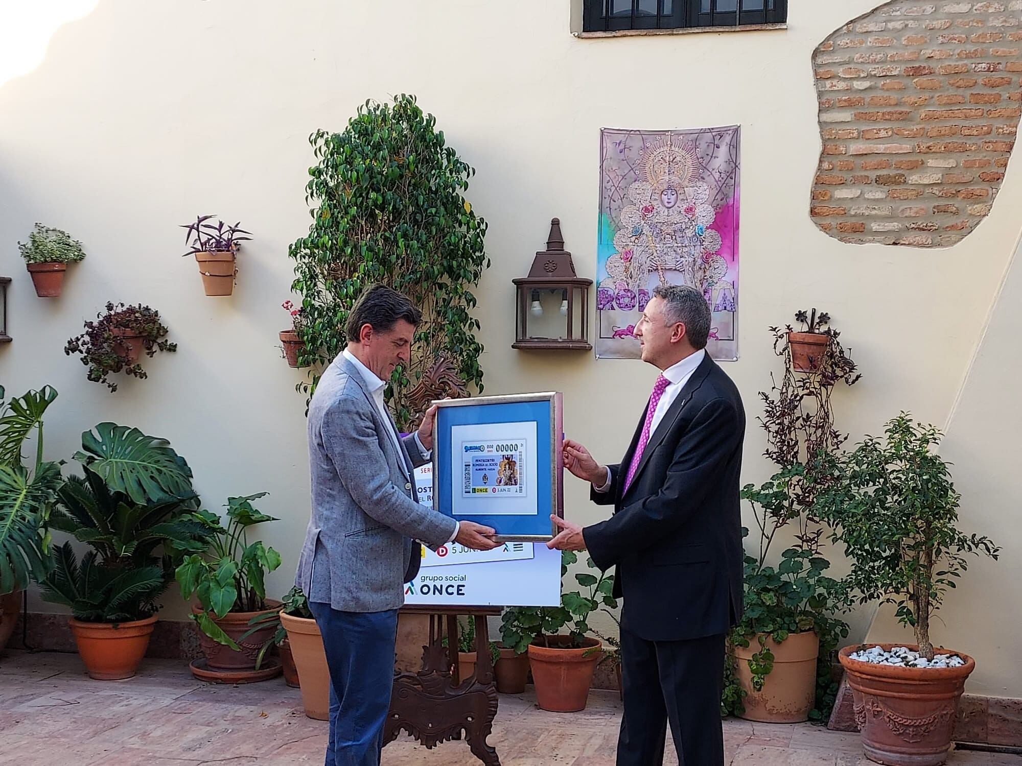 El presidente de la Hermandad Matriz de Almonte, Santiago Padilla -a la izquierda-, recibe un cuadro conmemorativo de manos de Cristóbal Martínez, delegado territorial de la ONCE en Andalucía