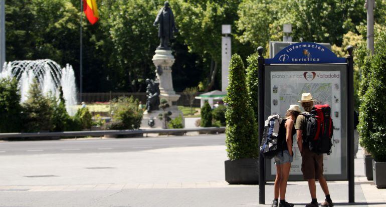 Una pareja de turistas observa un panel de información situado en la Plaza de Zorrilla