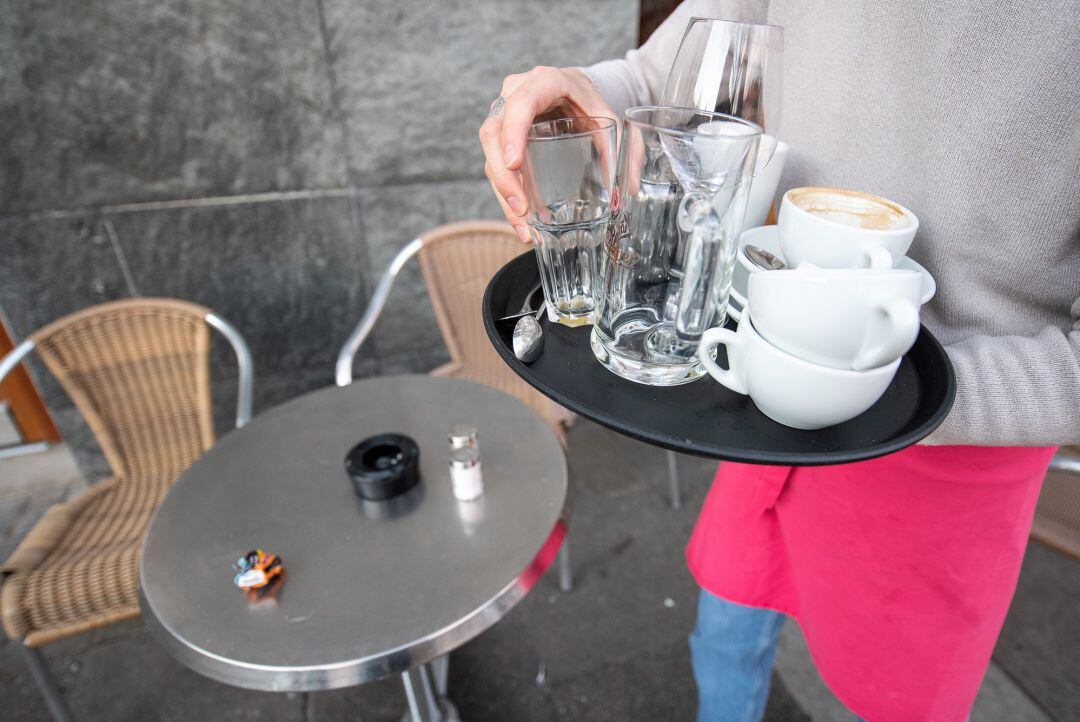 Un camarero recoge la mesa de una terraza.