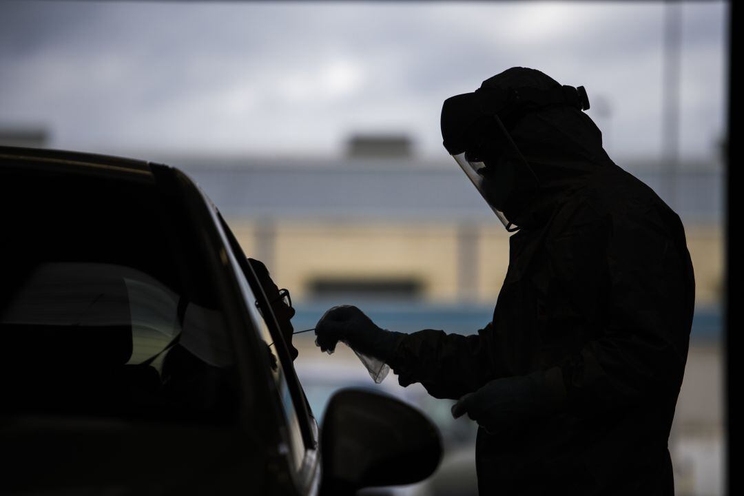 Un sanitario realiza una prueba PCR a un ciudadano desde su coche. 