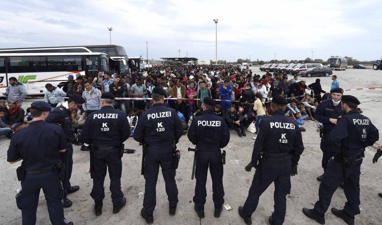 Agentes de policía vigilan a un grupo de refugiados en la frontera entre Hungría y Austria, en Nickelsdorf.