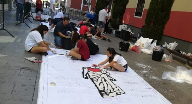 Inicio del relleno de la alfombra de la ONG Manos Unidas, en la calle Prado a las 9 de la mañana