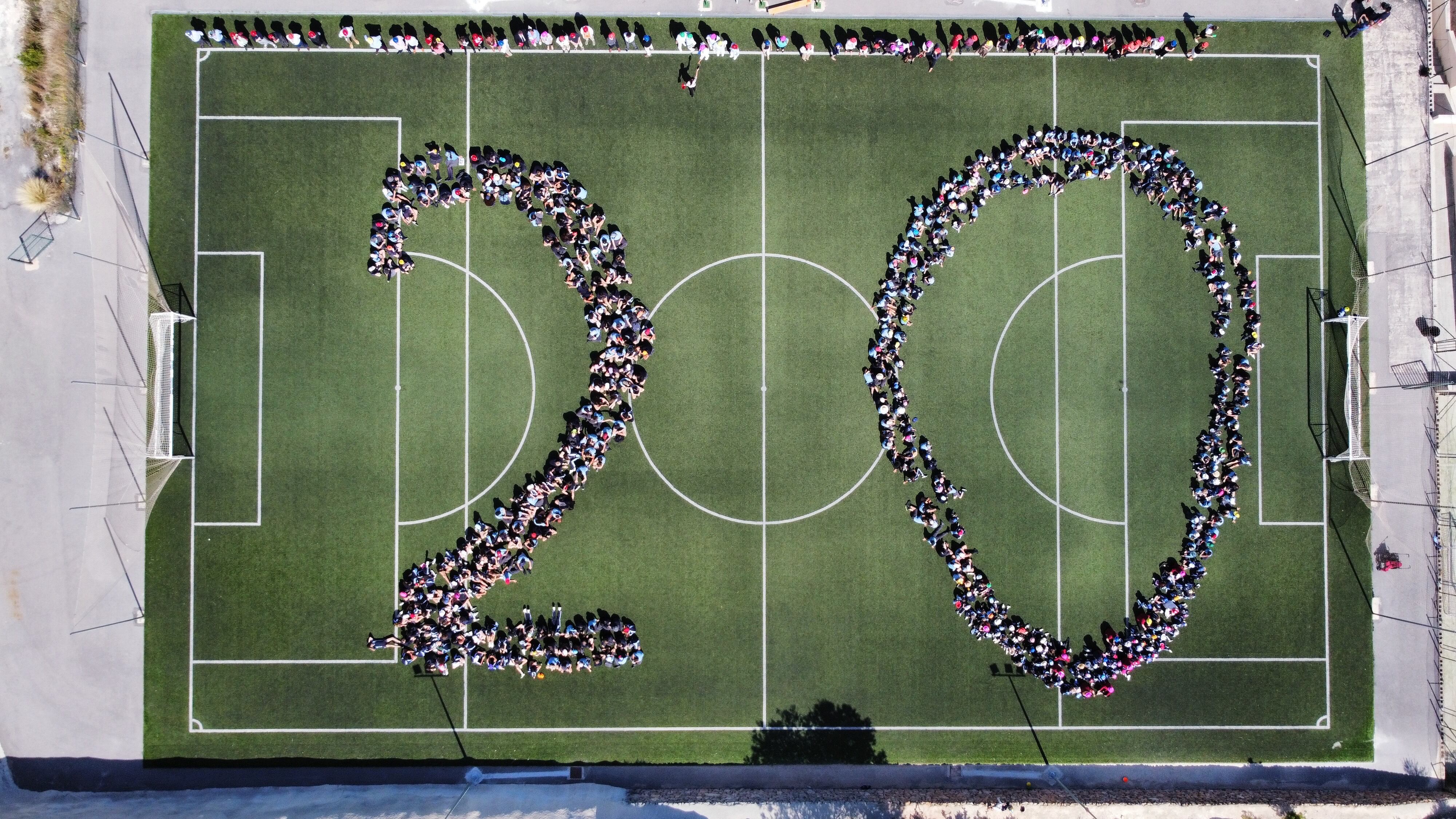 Todo el personal y alumnado del centro se unió en una foto dibujando un 20 en la pista de fútbol