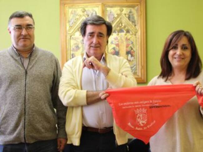 La concejal de Turismo muestra un pañuelo rojo con la palabra 'Internacional' escrita a mano. Acompañada del alcalde de Cuéllar y el concejal de Festejos