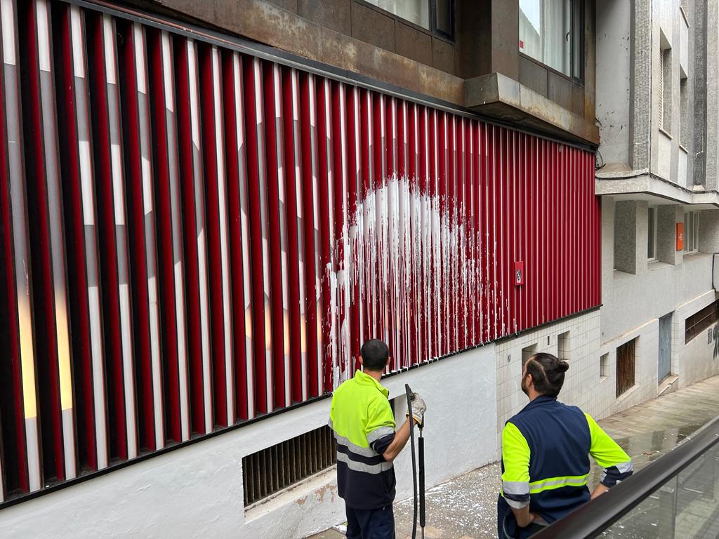 Operarios de limpieza retiran la pintada realizada en la sede del PSOE en Santander.