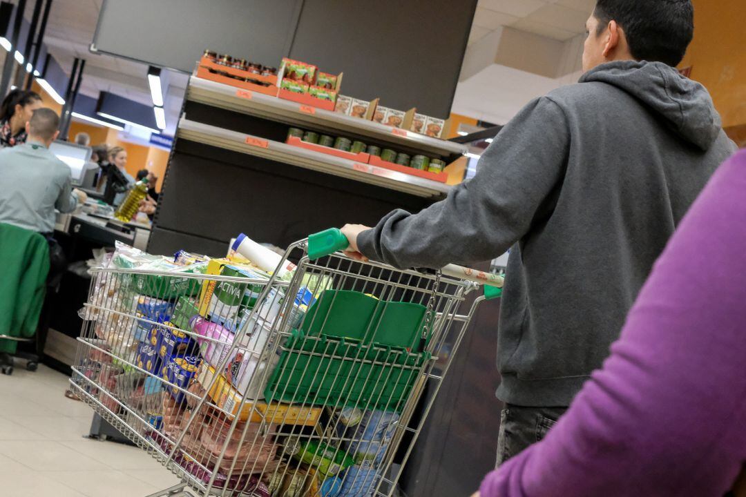 Un cliente realiza la compra en un supermercado un día marcado por colas de gente deseosas de hacer acopio de alimentos y otros productos debido al avance del coronavirus en Madrid