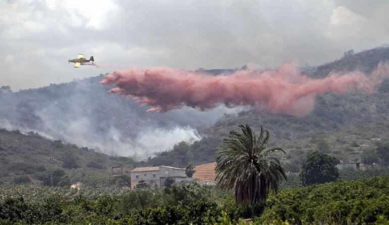 Una avioneta realiza una descarga sobre el frente del incendio forestal que amenaza una vivienda cerca de la localidad de Sumacarcer (Valencia), en el incendio de Bolbaite el pasado mes de junio