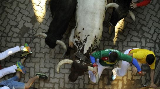 Runners sprint alongside Garcigrande fighting bulls at the entrance to the bullring during the seventh running of the bulls of the San Fermin festival in Pamplona, northern Spain, July 13, 2015. Two runners were gored in the run that lasted 2 minutes and 