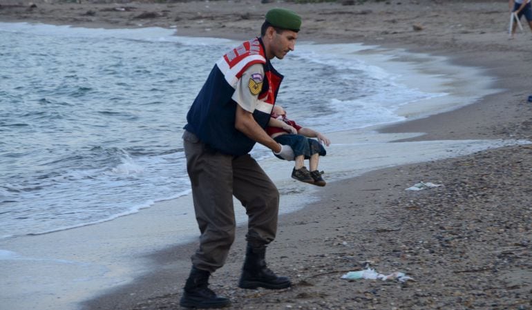 Un agente de la gendarmería turca recoge el cadáver del menor fallecido cauando intentaba llegar a Europa con su familia.