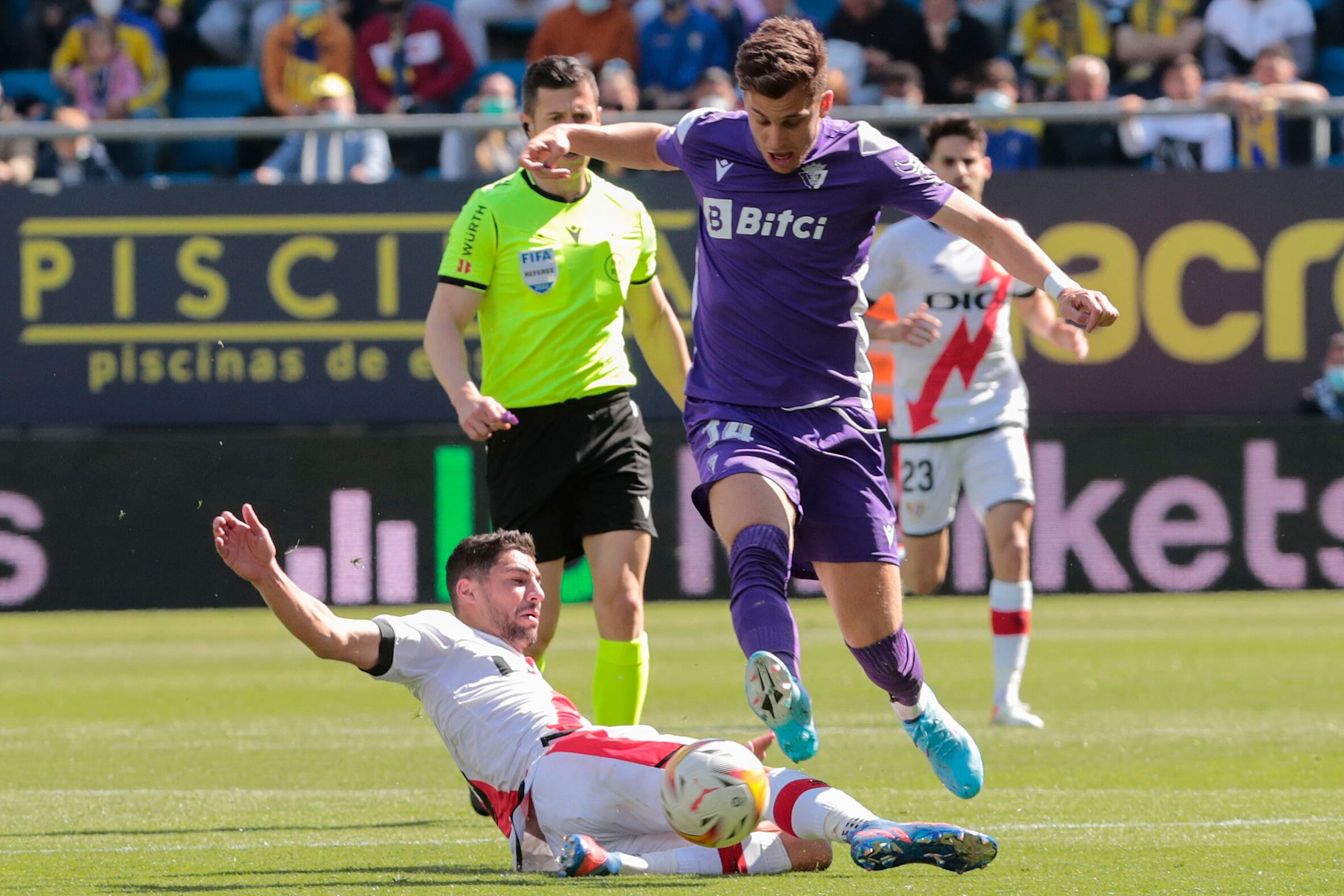 CÁDIZ, 06/03/2022.- El delantero del Cádiz CF, Alejo lucha por el balón con el centrocampista del Rayo Vallecano, Santi (en el suelo), durante el partido de Liga que enfrenta este domingo al Cádiz CF y al Rayo Vallecano en el Estadio Nuevo Mirandilla de Cádiz. EFE/Román Ríos