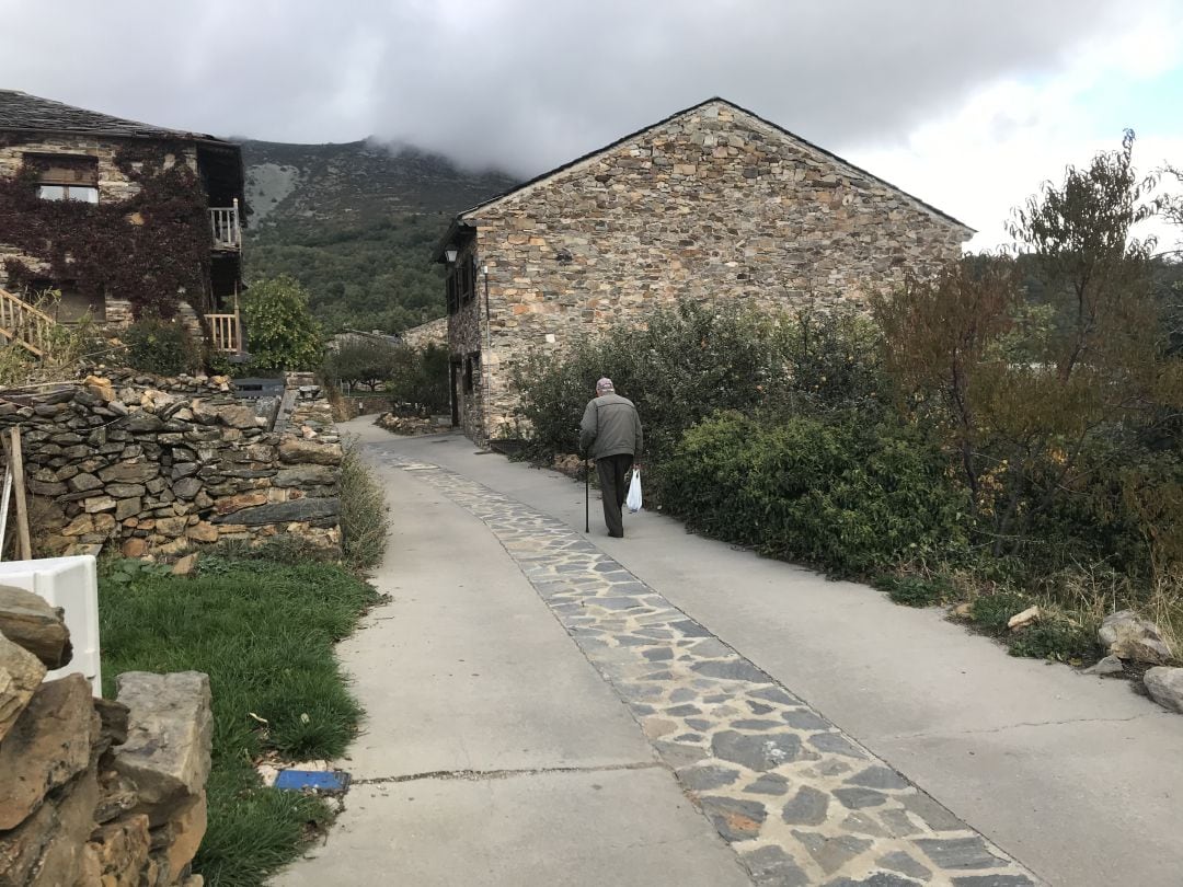 Una persona mayor camina por un pueblo pequeño.