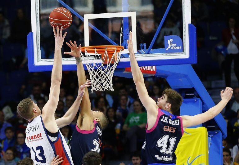 El pívot ucraniano del Rio Natura Artem Pustovyi (i) lanza a canasta ante los jugadores del Estudiantes Juancho Hernangómez (d) y el estadounidense Diamon Simpson, durante el partido de la vigésima octava jornada de liga ACB disputado ante el Rio Natura h