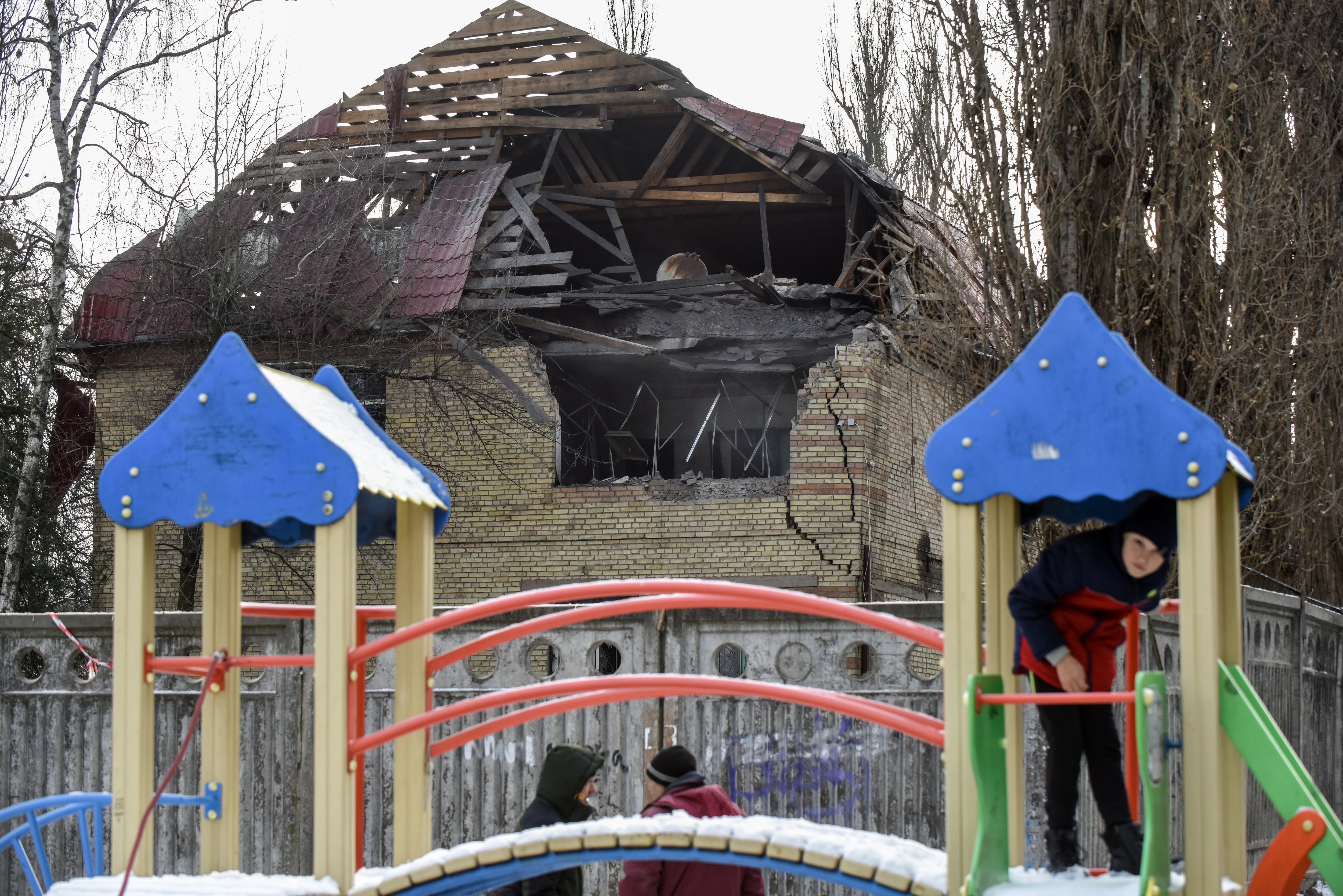 Niños jugando en un parque de Kiev (Ucrania) y de fondo un edificio destruido por un ataque con drone por parte de Rusia.