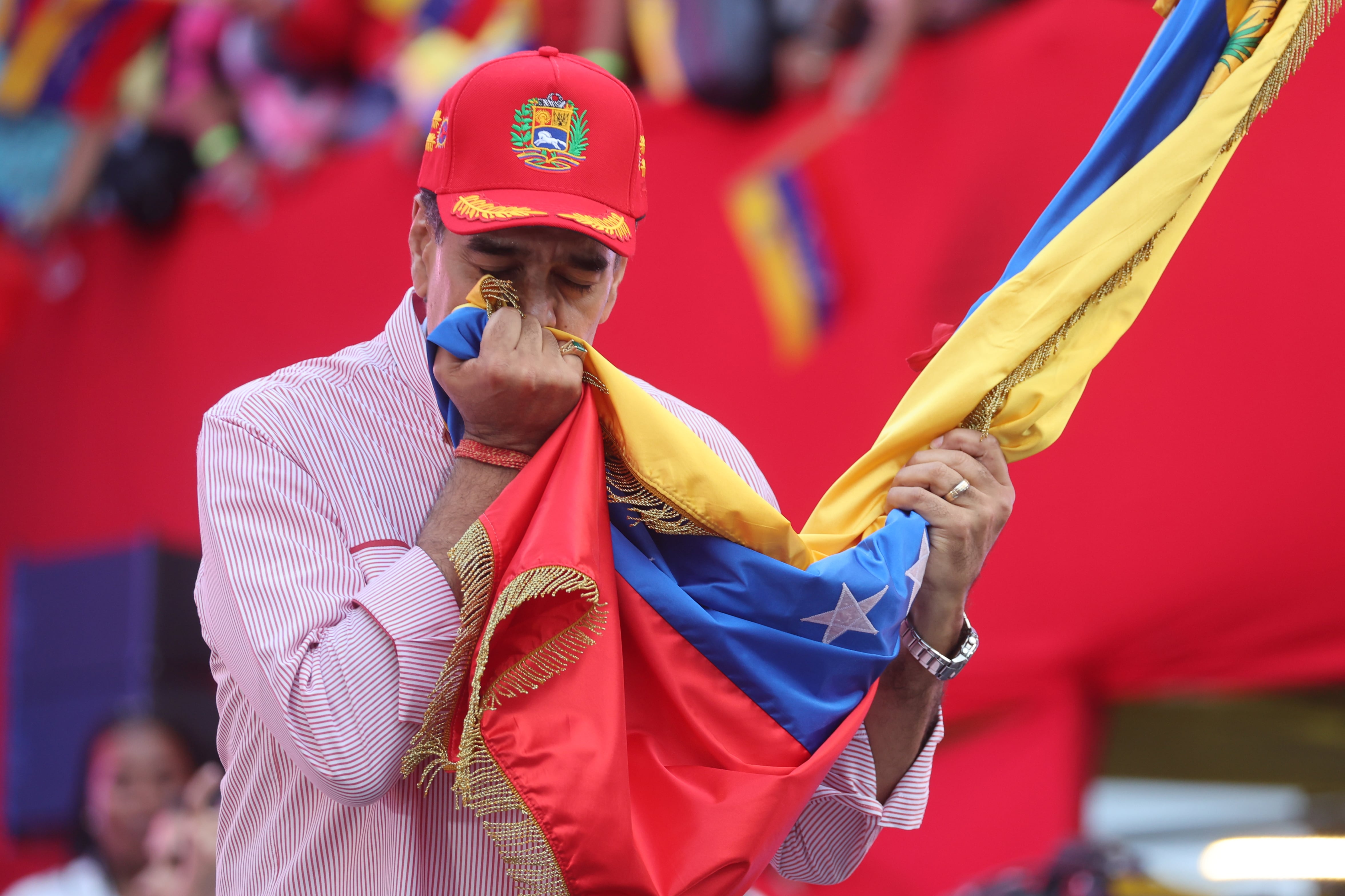 El presidente de Venezuela, Nicolás Maduro, besa una bandera durante una movilización este lunes, en Caracas (Venezuela). 