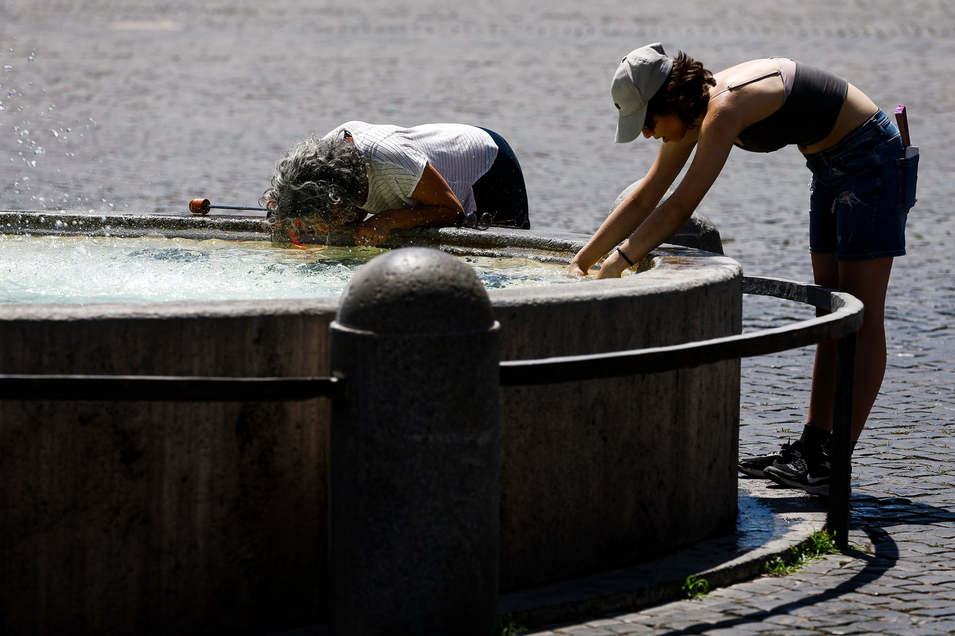 Dos personas se refrescan en una fuente de Roma en plena ola de calor
