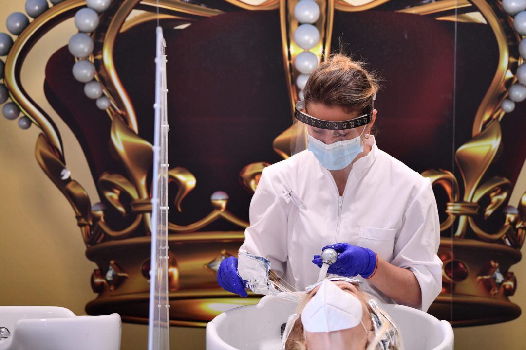 Una peluquera trabajando con mascarilla y guantes en una peluquería de Roma