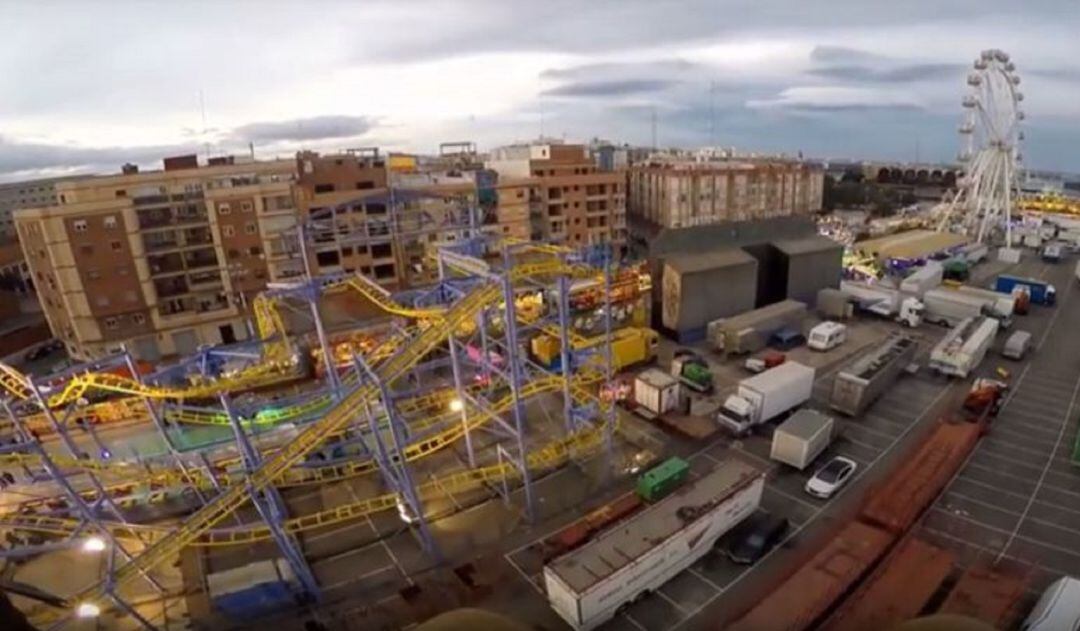 Imagen aérea de la feria de atracciones que se instala en el Grao con los edificios de viviendas al fondo