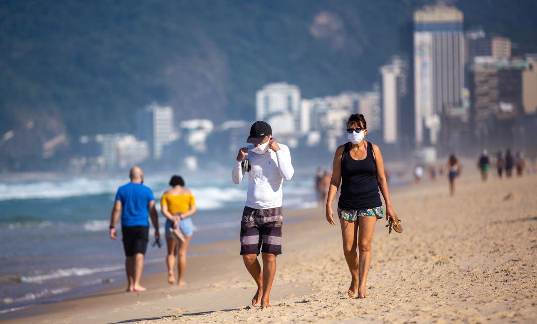 Personas con mascarillas en la playa.