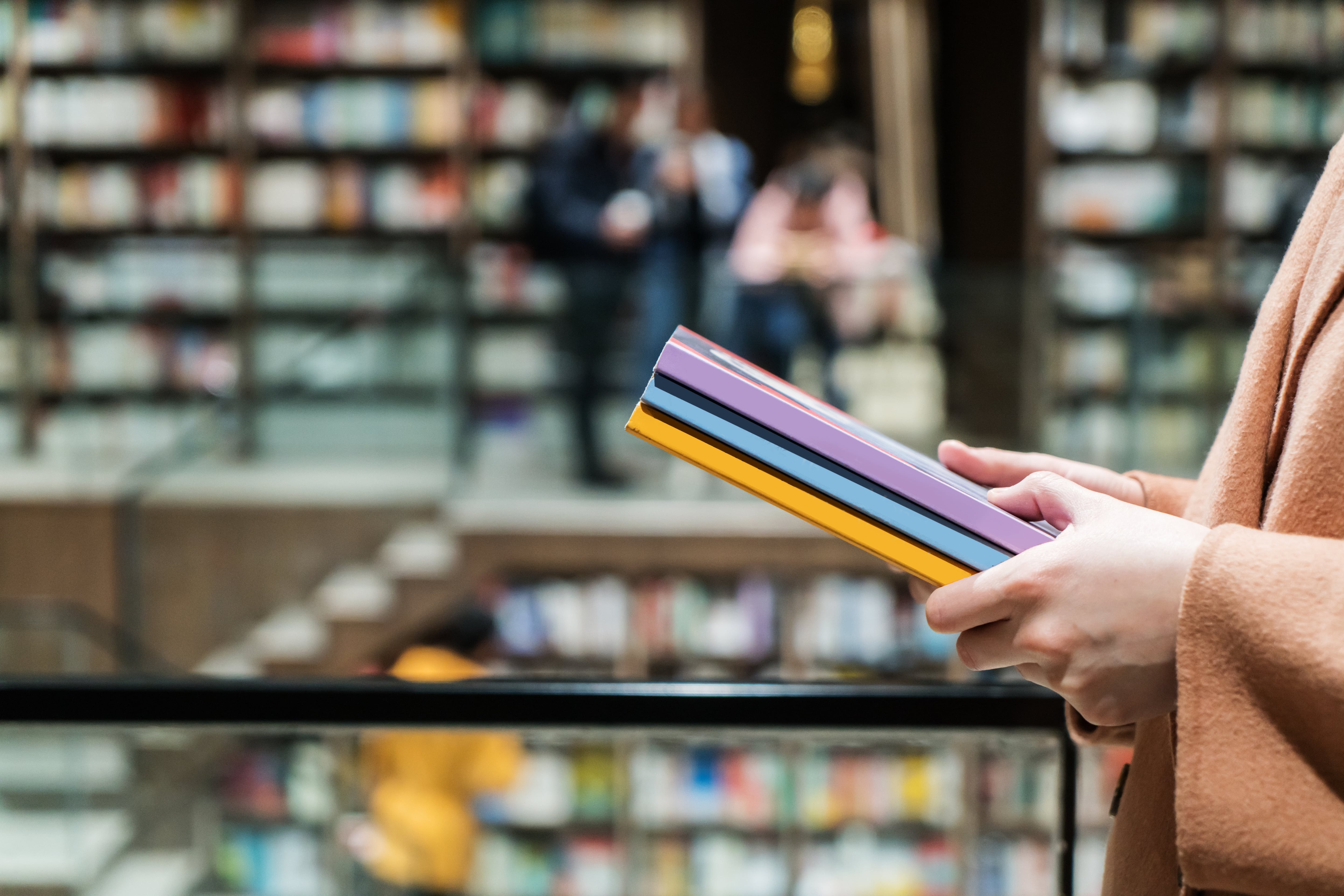 Una persona sujeta varios libros en una librería.