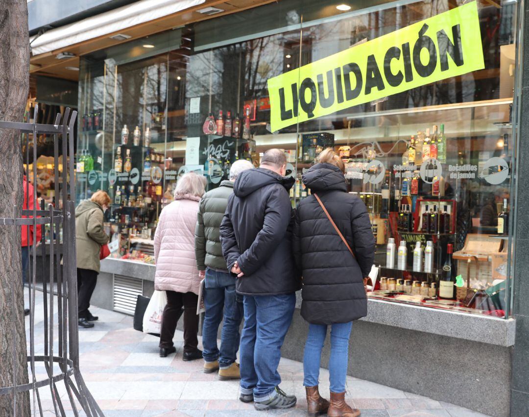 Varias personas observan el escaparate de un comercio.