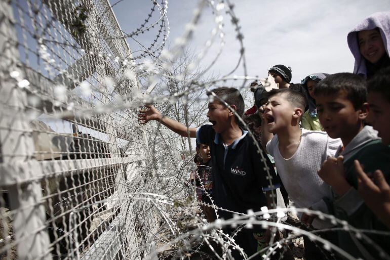  Varios niños se manifiestan en frente de la alambrada por la apertura de las fronteras a Macedonia en el campo improvisado de refugiados de Idomeni