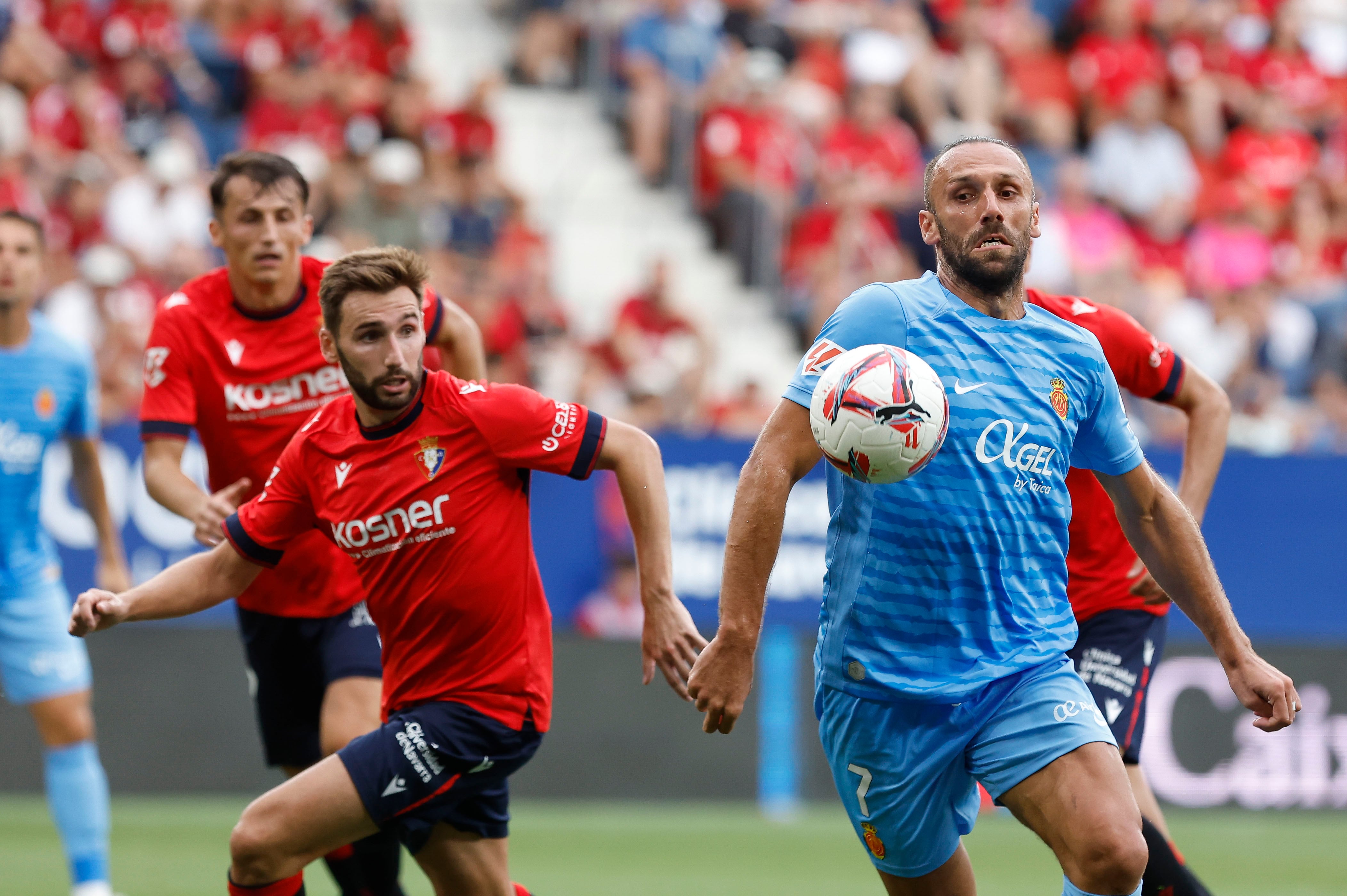 PAMPLONA, 24/08/2024.- El centrocampista del Osasuna Jon Moncayola (i) lucha un balón con el delantero kosovar del Mallorca Vedat Muriqi durante el partido de la segunda jornada de Liga de Primera División disputado este sábado en el estadio de El Sadar. EFE/Villar López
