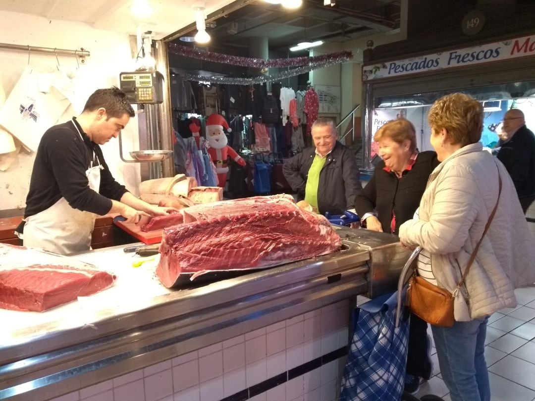 Un pescatero del Mercado Central trocea un atún en plena jornada de Nochebuena.