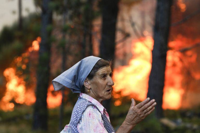 Una mujer observa el fuego en Carvalheda, Vale de Cambra, Portugal, un fuego comabtido con 113 efectivos, 37 vehículos terrestres y dos refuerzos aéreos