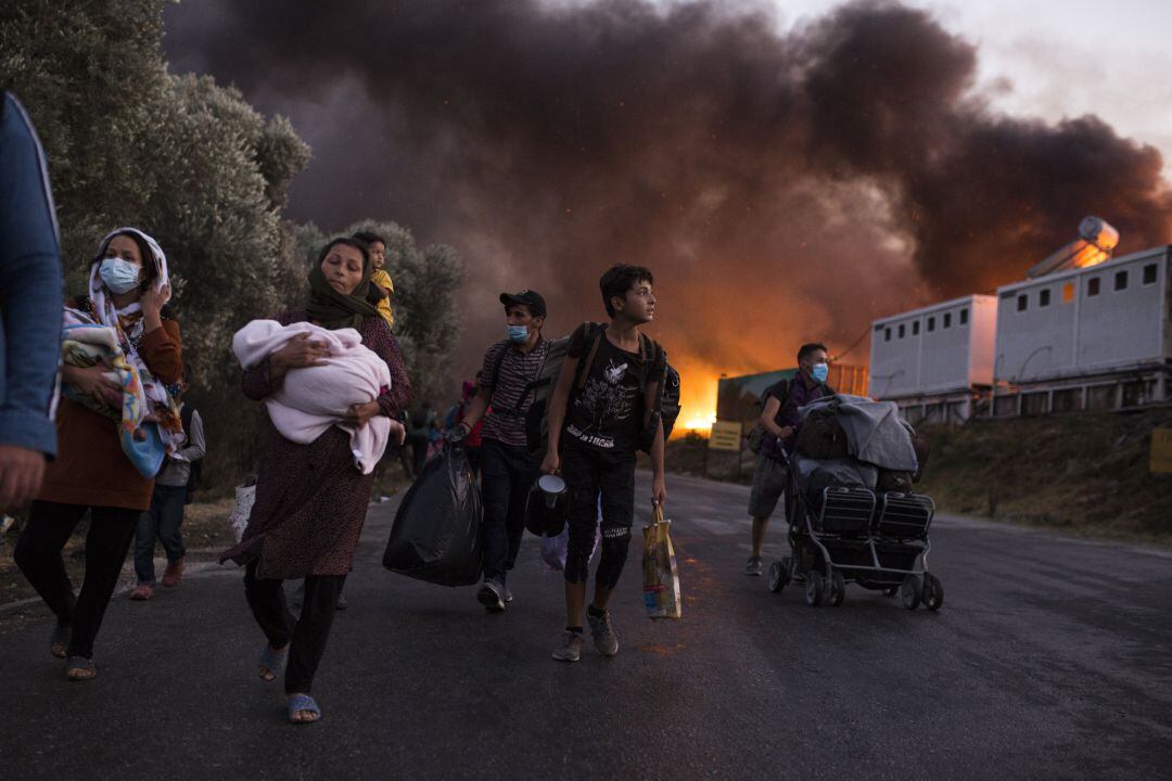 Refugiados con sus pertenencias huyen de Moria tras el incendio en el campamento