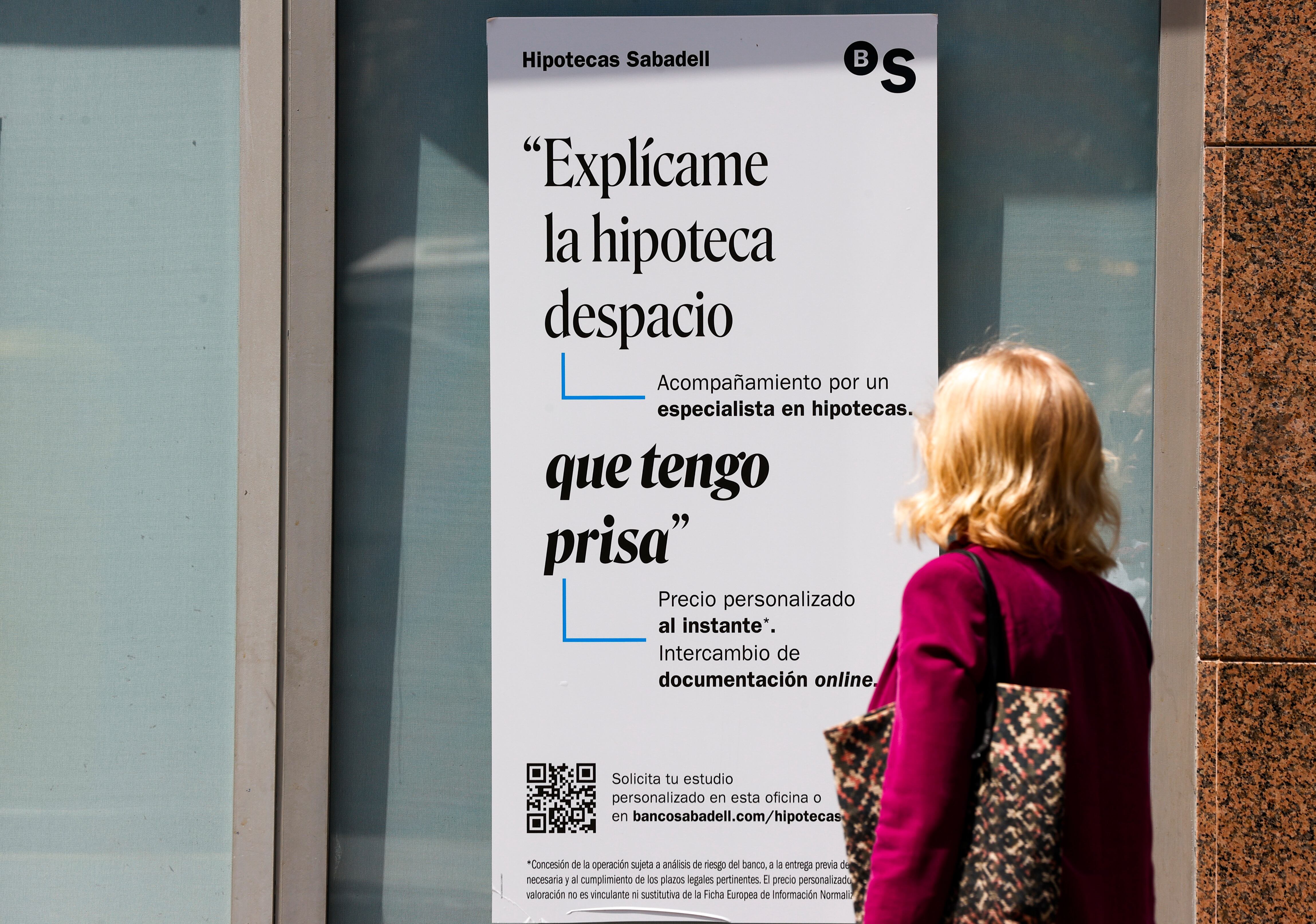 . BILBAO, 26/05/2023.- Una mujer ante un cartel bancario sobre las hipotecas. El pasado mes de marzo se firmaron en España 36.182 hipotecas para la compra de viviendas, un 15,7 % menos que en el mismo mes de 2022, el mayor descenso desde enero de 2021, según los datos publicados este viernes por el Instituto Nacional de Estadística (INE). EFE/Luis Tejido
