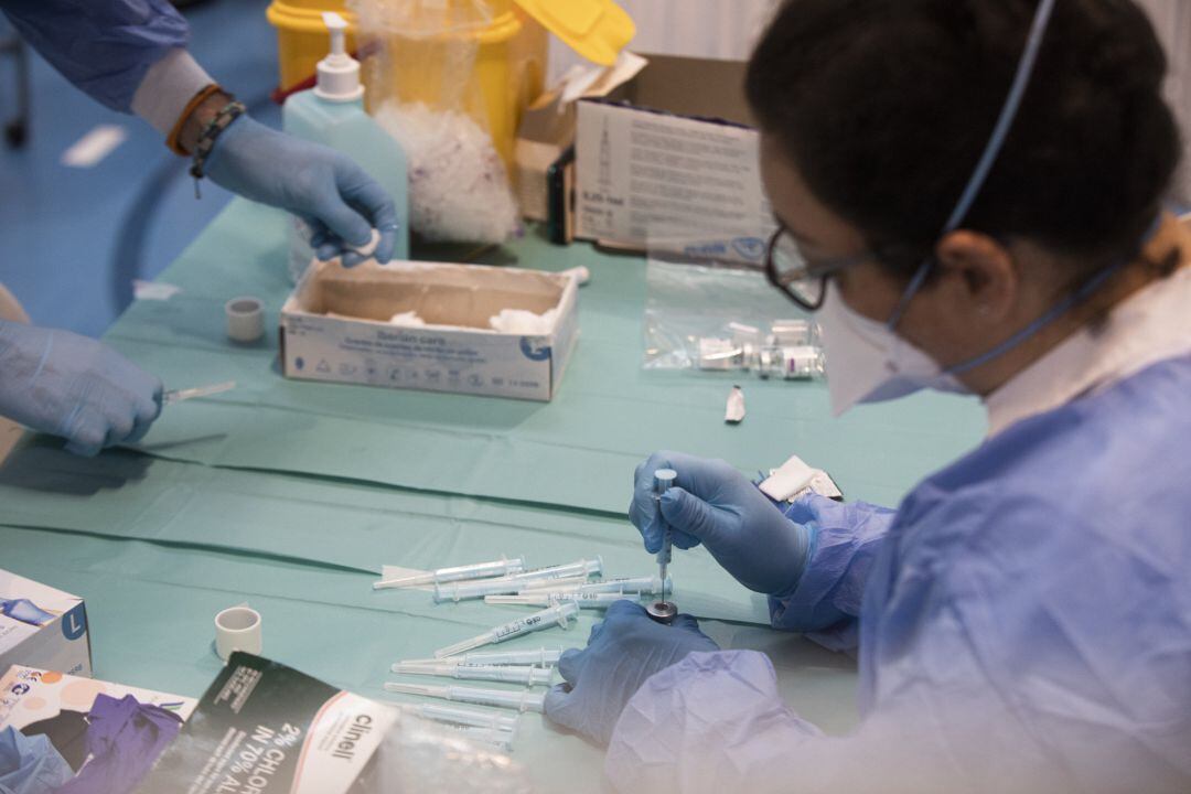 Una profesional sanitaria sostiene una jeringuilla con un vial de la vacuna contra la COVID-19 de AstraZeneca, foto de recurso