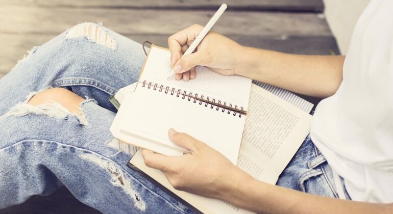 Imagen de una chica escribiendo en un cuaderno.