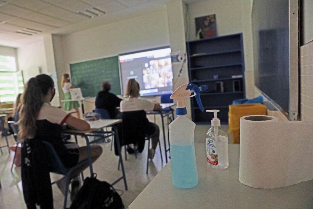 Productos desinfectantes colocados en los pupitres desde donde los alumnos atienden a las clases 