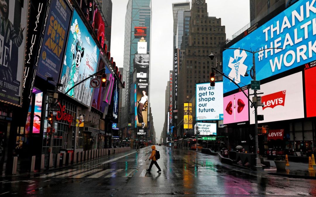 Fotografía fechada el 24 de marzo de 2020 de un hombre caminando por un Times Square totalmente vacío a causa del coronavirus en Nueva York, EEUU. 