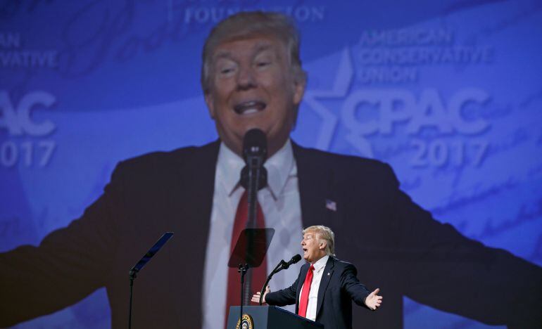 Con su imágen proyectada en la pantalla, el presidente Trump habla en la conferencia de CPAC en Maryland